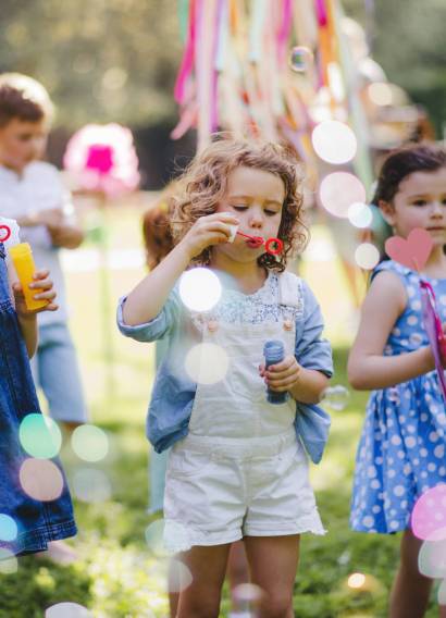Small children outdoors in garden in summer, playing with bubbles. Small children outdoors in garden in summer, playing with bubbles. A celebration concept.